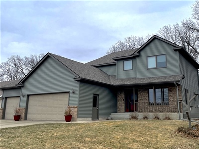 A modern two-story house with a gray exterior and double garage, set against a barren lawn and overcast sky.