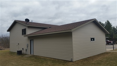 A beige split-level home with a large attached garage, set against a barren landscape and an overcast sky.