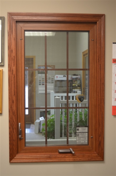  A wooden framed window with nine panes, reflecting an indoor office setting with furniture and plants visible in the background.
